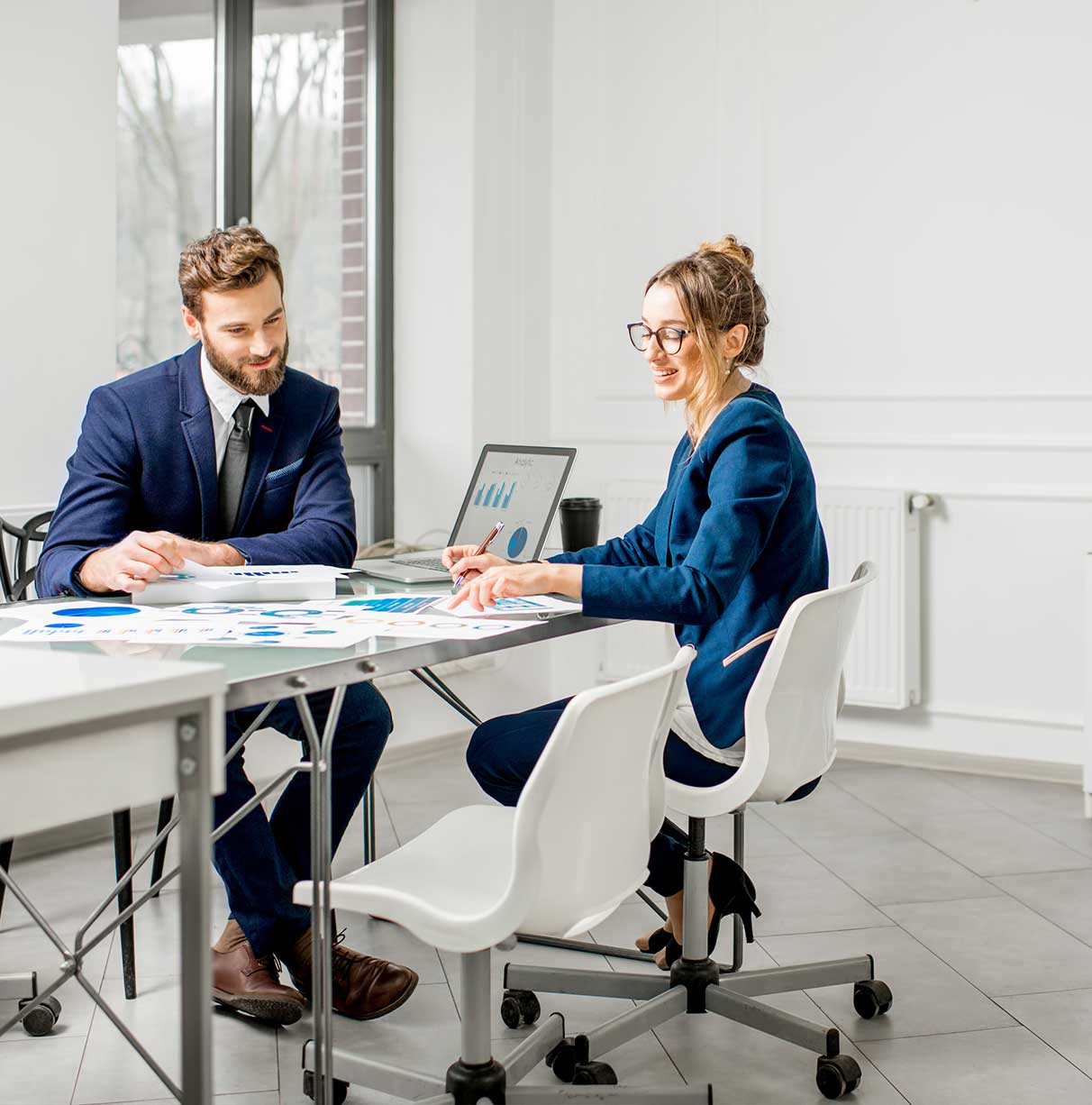 Two people seated at desk, reviewing charts